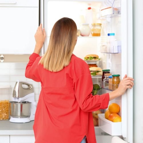 Woman looking into refrigerator while considering food choices